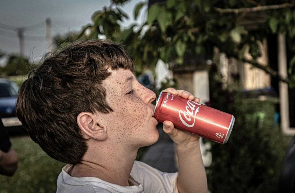 bambini che beve cocacola in lattina