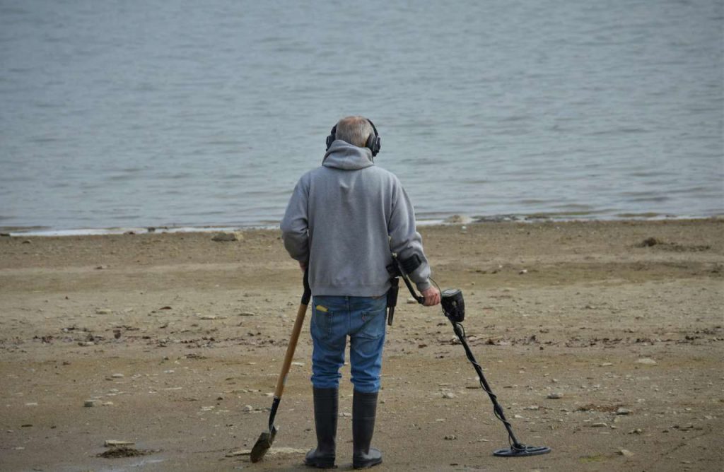 uomo su spiaggia con metal detector
